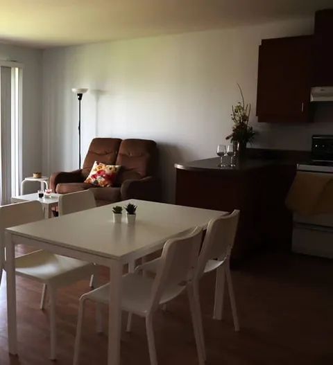 Room with a table, chairs, an armchair and a kitchen area