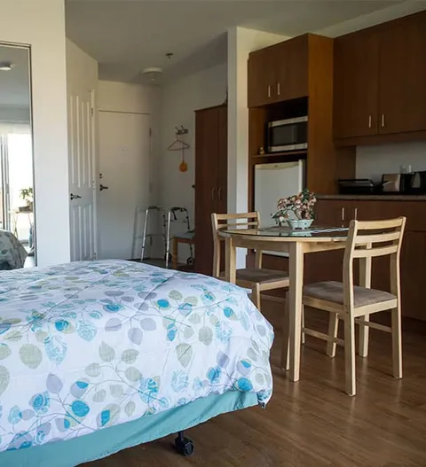 Apartment with a bed, dining table, chairs and a kitchen area