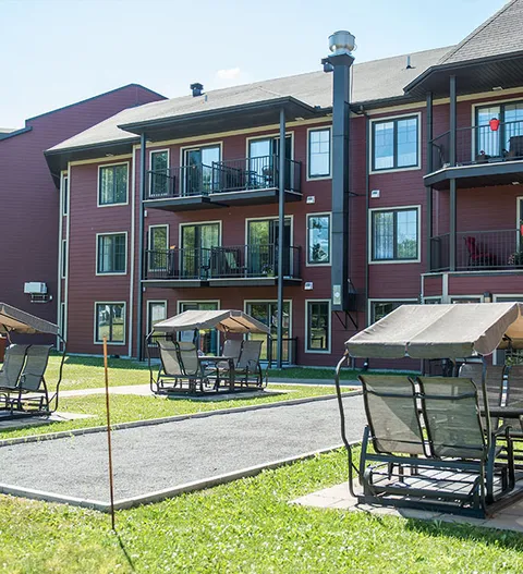 Building with balconies beside a lawn and covered garden seats