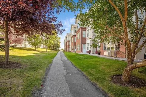 Path beside the residence with grass, trees and ground-floor patios
