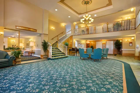 Lobby with blue armchairs, a piano, staircase and upper balcony