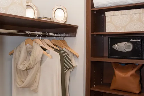 Open wardrobe with hanging clothes, shelves and a built-in safe