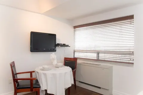 Small dining area with two wooden chairs, a round table and a television
