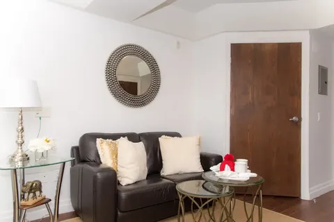 Sitting area with a black sofa, round mirror and small glass tables