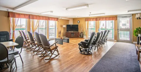 Room with rocking chairs facing a blank television, tall windows and yellow curtains