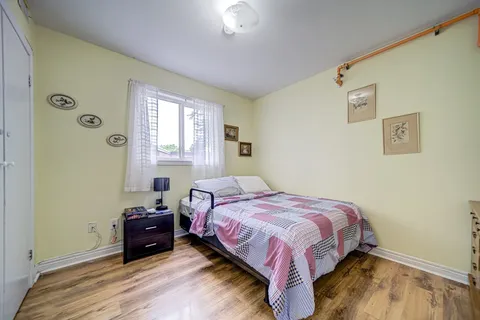 Bedroom with a plaid bed cover, a dresser and framed wall pictures