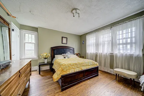 Bedroom with a bed, yellow cover, mirrored dresser and bedside furniture