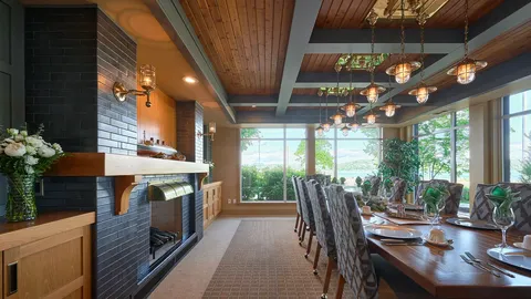 Dining room with a long wood table, patterned chairs and a fireplace.