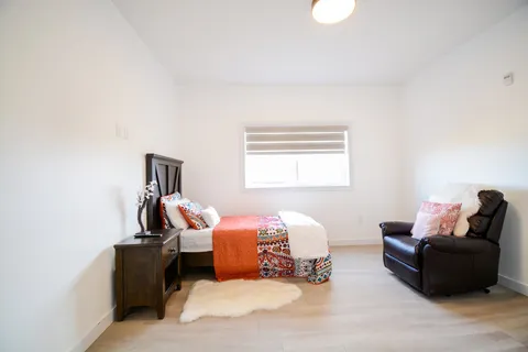 Bedroom with a bed, an orange throw, a reclining armchair and a window