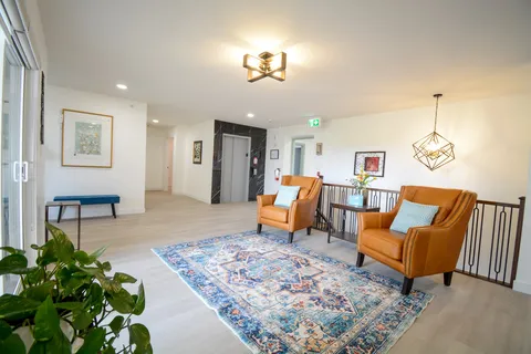 Upper-floor seating area with tan armchairs, a patterned rug and a lift