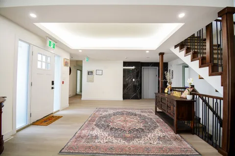 Foyer with a patterned rug, wooden staircase, console table and lift