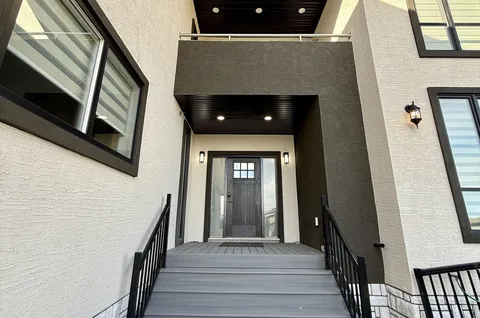 Covered entrance with a wooden door, sidelights, steps and metal handrails