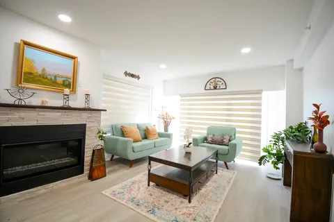 Sitting room with green seating, a fireplace, landscape artwork and striped blinds