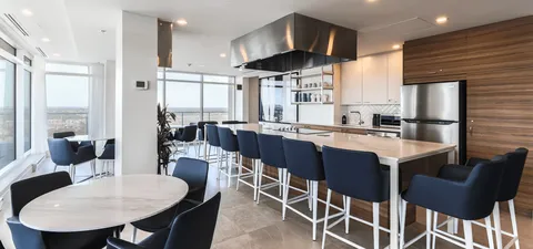 Kitchen counter with tall stools, cabinets and round dining tables