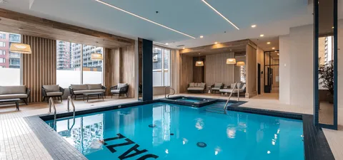 Indoor swimming pool with blue tiles and seating beside large windows