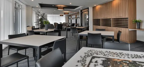 Room with tables, chairs, a jigsaw puzzle and large windows