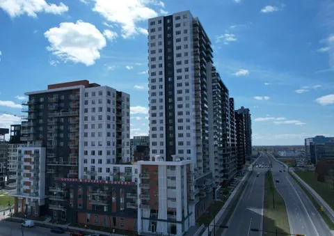 Tall residence buildings beside a road under a cloudy sky