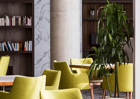 Library seating with green armchairs and built-in bookshelves.