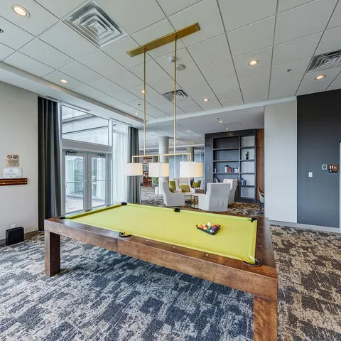 Billiards room with a pool table and seating by the windows.