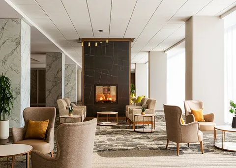 Lounge with armchairs around a stone fireplace.
