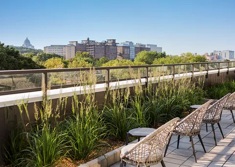 Planted terrace with woven chairs and a view across the neighbourhood.