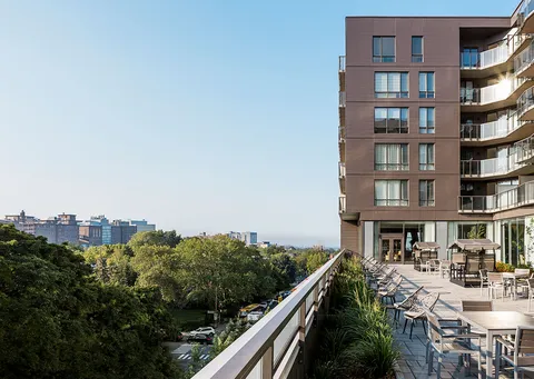 Residence exterior and terrace overlooking trees and nearby buildings.