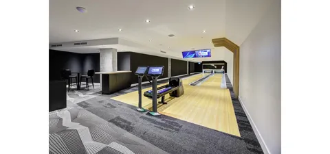 Two bowling lanes with scoring screens and seating beside a counter