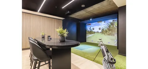 Golf simulator room with clubs, a projected course and a high table