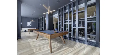 Billiards table in a tall room with windows, wood flooring and wall art