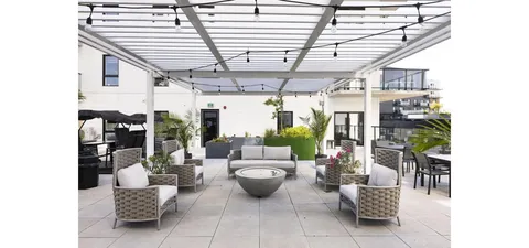 Covered terrace with wicker seating, tables and potted plants