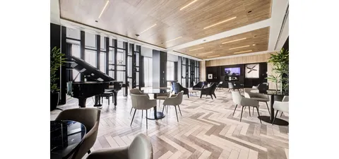 Lounge with a grand piano, armchairs and small tables beneath a wooden ceiling