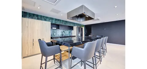 Kitchen with an island, grey bar stools, cabinets and a stainless steel range hood
