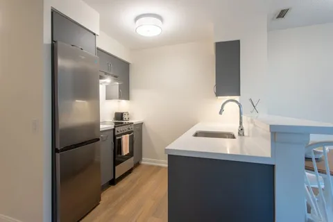 Kitchen with wooden cabinets, stainless appliances and stone counters