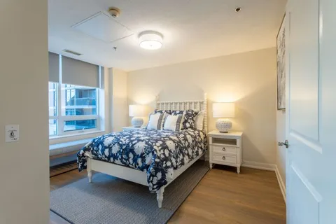 Bedroom with a blue patterned bed cover, bedside tables and lamps
