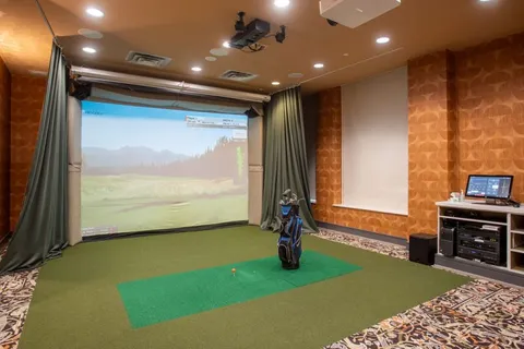 Golf simulator room with a putting mat and a landscape on the screen