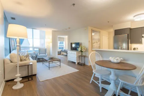 Sitting area with a sofa, television, dining table and kitchen cabinets