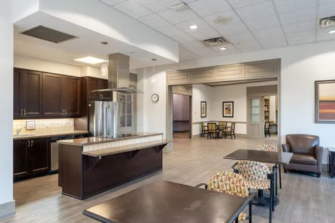 Room with tables, armchairs, an island and kitchen cabinets