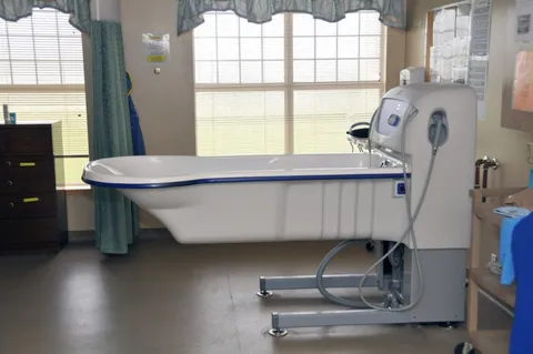 Bathroom with a bathing tub, lifting equipment and large windows