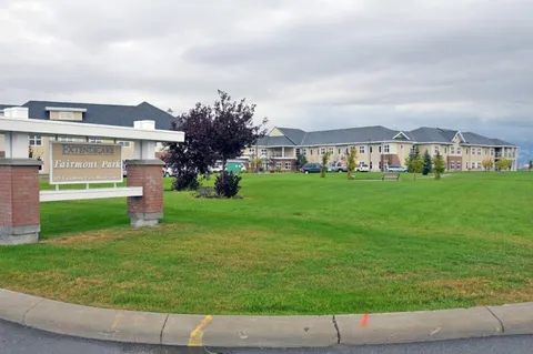Building behind a lawn, shrubs and a roadside residence sign