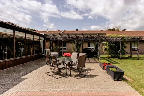 Paved patio with a table, chairs, flower planters and a pergola