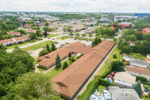 Aerial view of a low-rise residence with a long brown roof, courtyards and trees