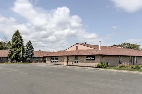Low-rise brick building with a brown roof beside a paved parking area