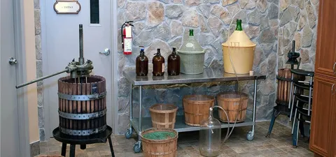 Wine presses, wicker-covered vessels and buckets against a stone wall