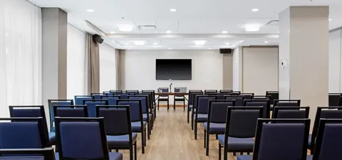 Rows of chairs facing a television in a bright room