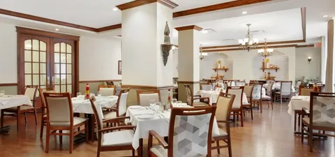 Dining room with set tables and upholstered wooden chairs