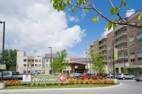 Multi-storey brick building with a covered entrance and parked vehicles