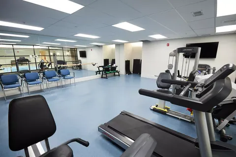 Fitness room with exercise machines, chairs and a mirrored wall