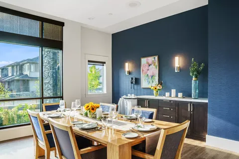 Dining table with upholstered chairs beside large windows