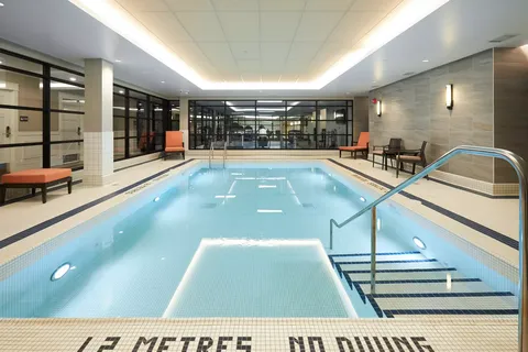 Indoor swimming pool with steps, handrails and poolside chairs