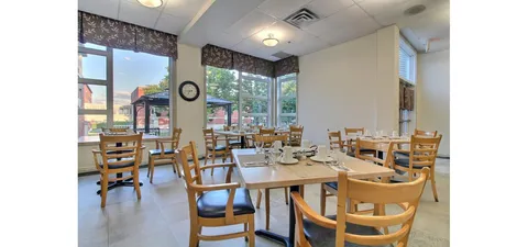 Dining room with set tables beside broad windows.